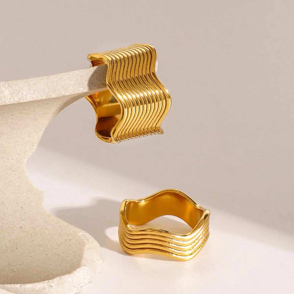 Geometric stainless steel ring with wide band and wave pattern design.