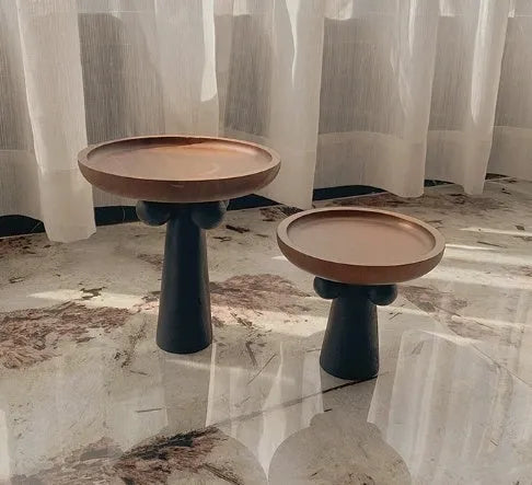 Round high-legged wooden tray in modern style holding a candle and perfume bottle for home decor.