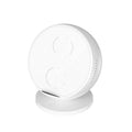 Black multifunctional wireless charging phone holder with built-in Bluetooth speaker on a desk.