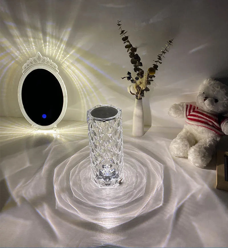 Clear acrylic crystal rose shaped LED table lamp with diamond-like facets on a table.