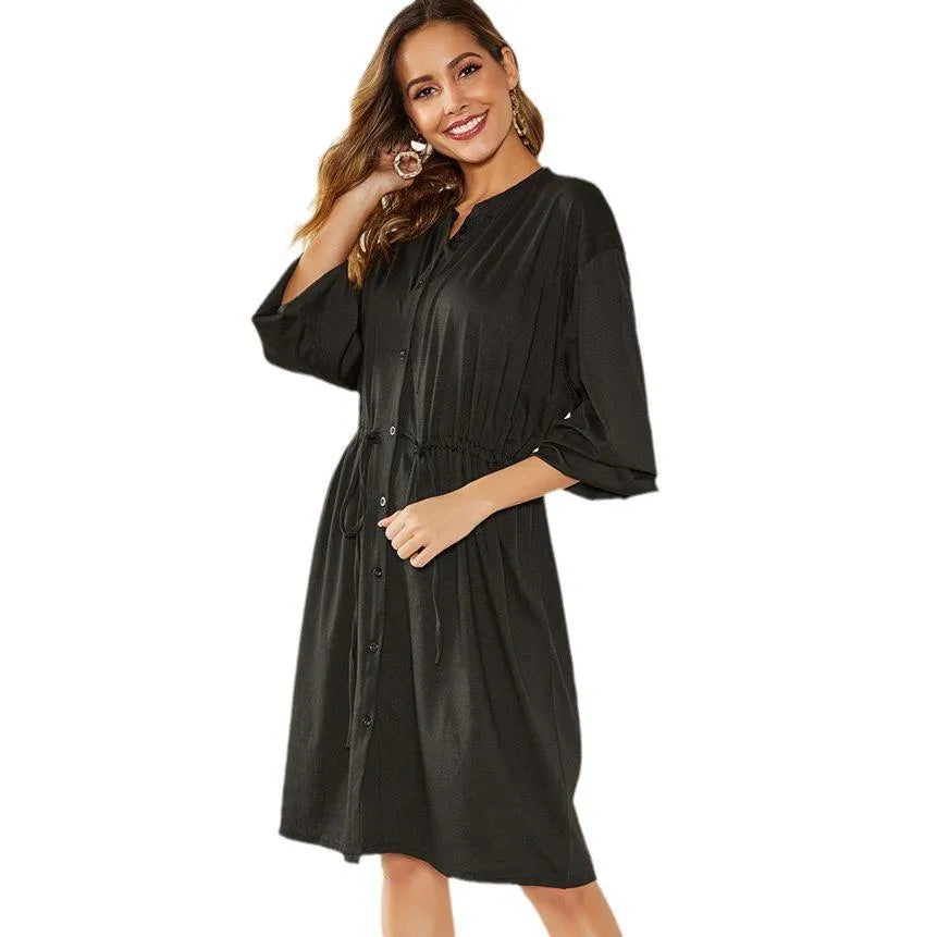 A woman's solid-colour A-line dress with long sleeves, elastic cuffs, an elastic waist, and a cinched belt.