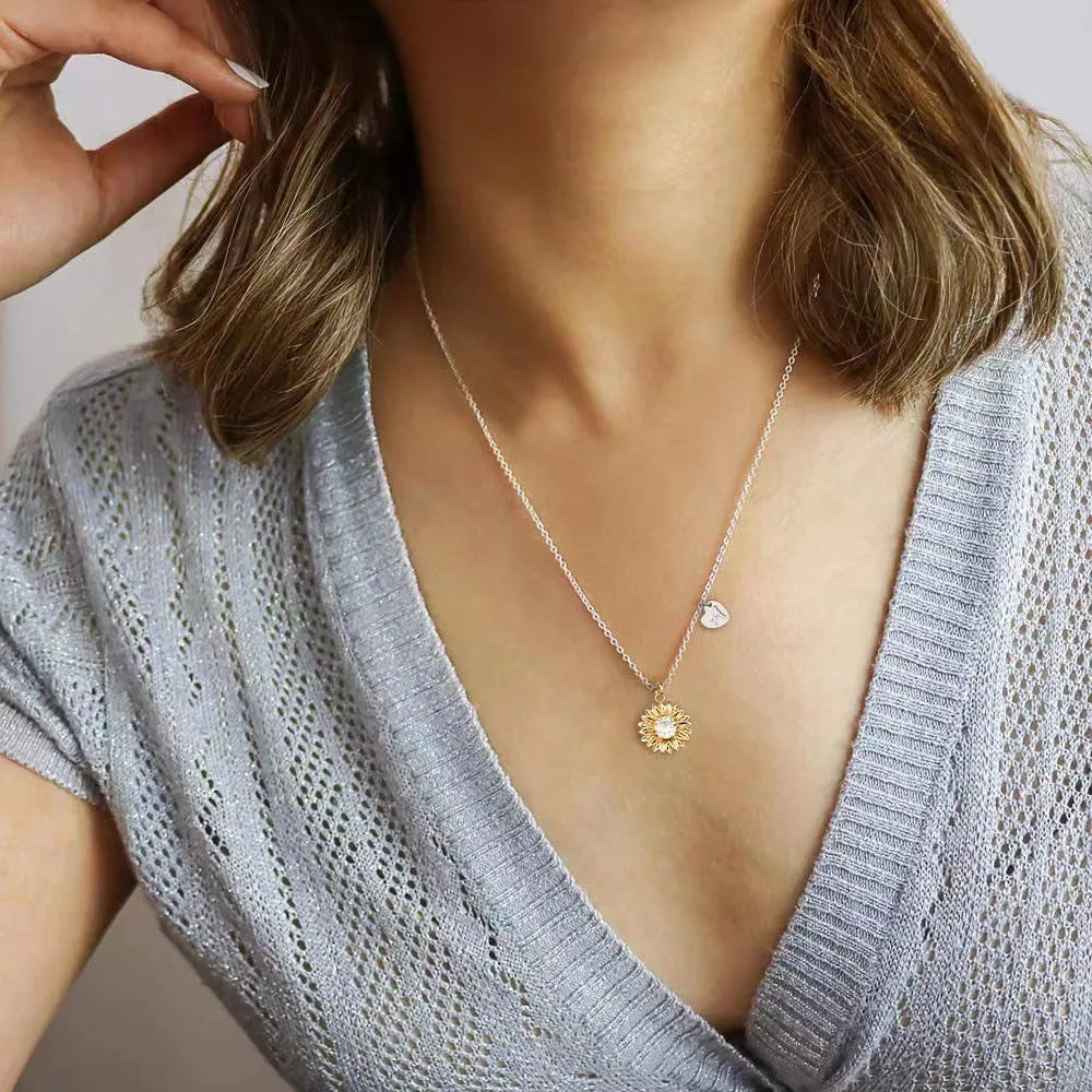 Close-up of a geometric sunflower pendant necklace on an adjustable silver cross chain.