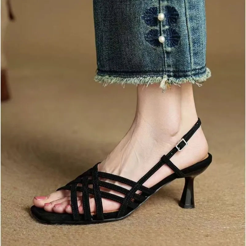 Light brown women's sandals with thin cross-straps, an ankle buckle, and a 3-6cm mid heel on a wooden floor.