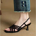 Light brown women's sandals with thin cross-straps, an ankle buckle, and a 3-6cm mid heel on a wooden floor.