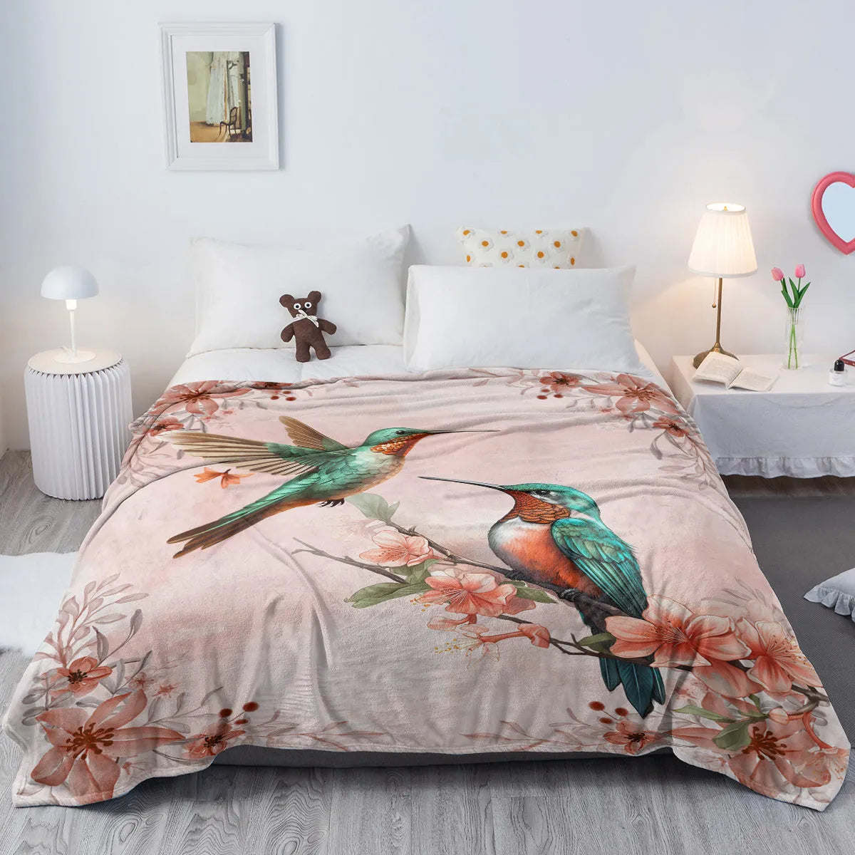 Pink hummingbird floral fleece throw blanket made of soft flannel velvet, folded on a sofa