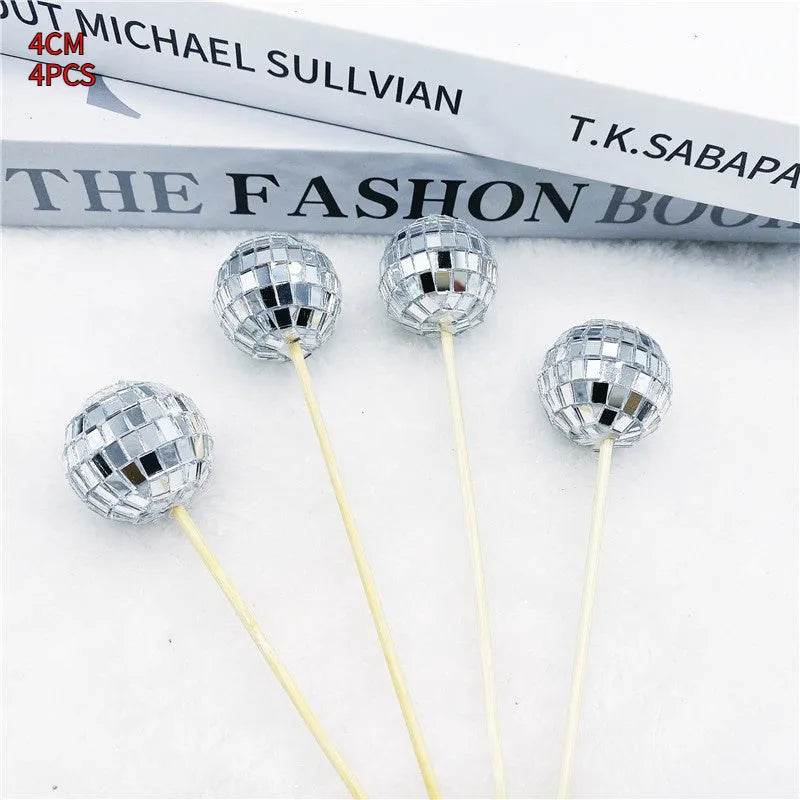 Small glass mirrored disco ball cake decoration attached to a thin wooden stick.
