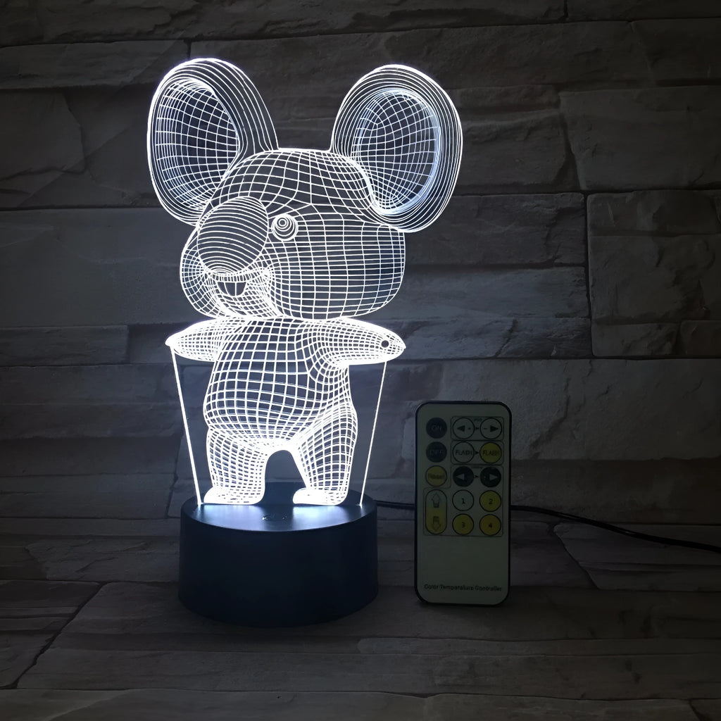 Black koala-shaped LED night light with remote control on a table.