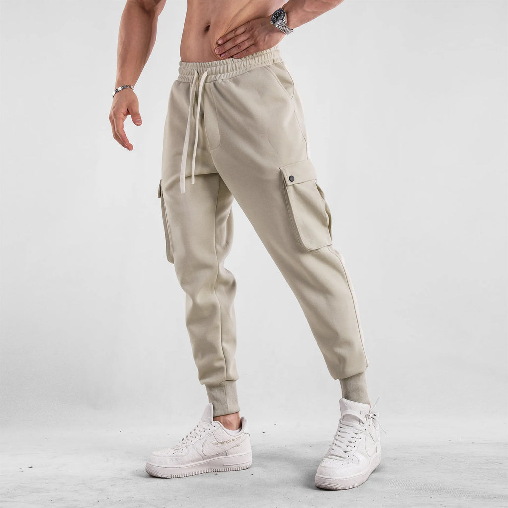 Men's loose-fit apricot coloured cotton sports trousers with an ankle tie and side pockets on a neutral background.