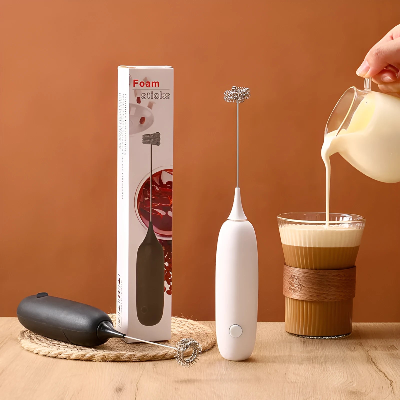 A handheld electric milk frother and blender in black and white colours on a kitchen counter.