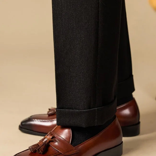 Men's black and brown polished leather tassel loafers for business casual wear, shown from the side.