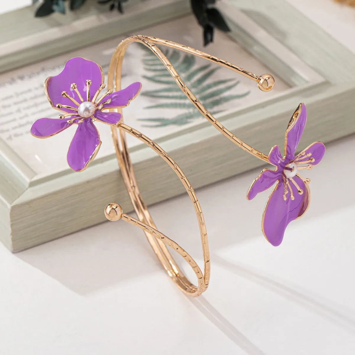 Pink hollow metal bangle with engraved pattern on a wrist, showing its open design and lightweight profile.