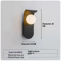 Modern minimalist wall lamp in black finish with LED warm light on a bedroom wall beside bed