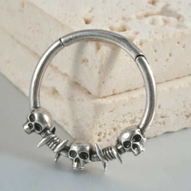 A pair of antique silver copper punk earrings featuring three small detailed ghost heads on a horizontal bar.