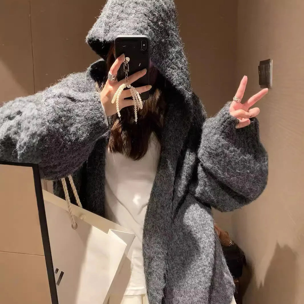 Woman wearing a brown retro-style chunky knit hooded cardigan with a loose fit.