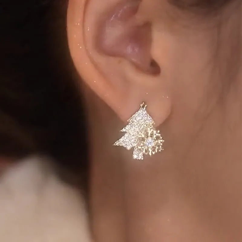 Pair of rotatable Christmas tree stud earrings with rhinestone snowflake detail in gold on a white background