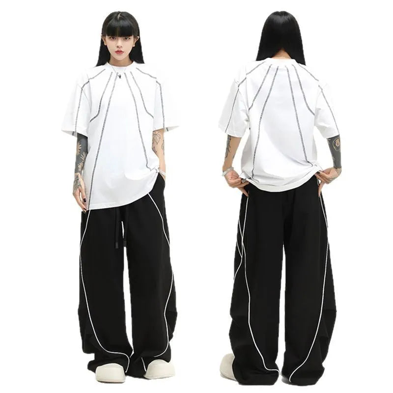 Black sports trousers with white stripes, showing wide-leg loose fit and mid-waist design.