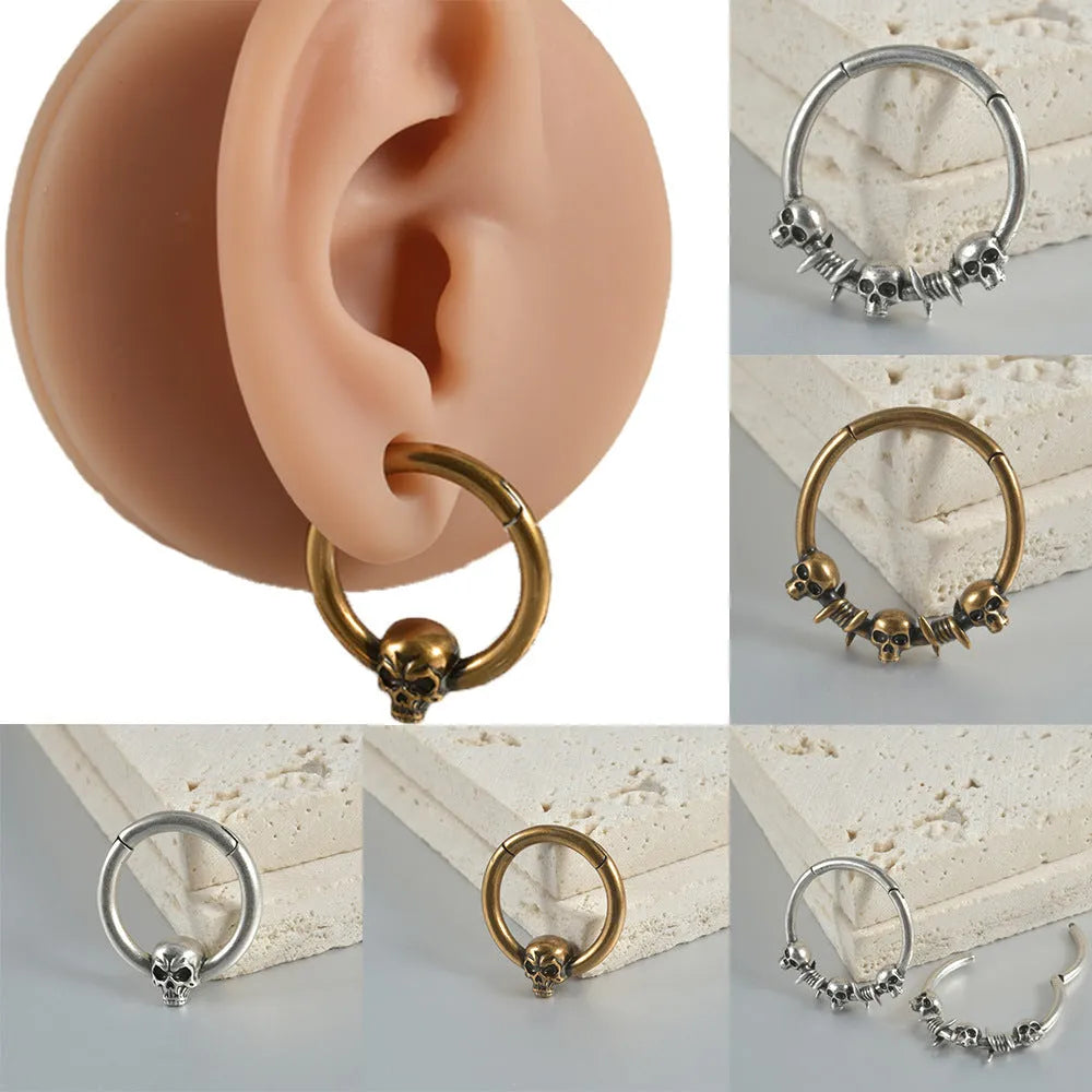 A pair of antique silver copper punk earrings featuring three small detailed ghost heads on a horizontal bar.