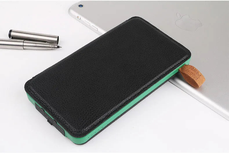 Outdoor solar power bank in black with a solar panel, soft leather finish, and LED light on a grassy field.
