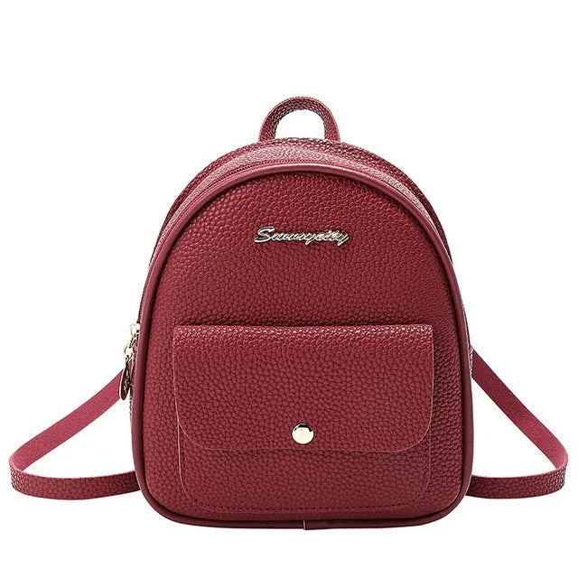 A small black PU women's shoulder backpack with a zip, shown next to a mobile phone for scale.