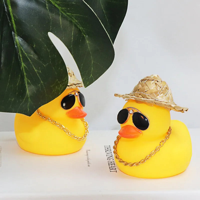Straw hat yellow duck car ornament with adhesive gel and miniature sunglasses accessory on car dashboard