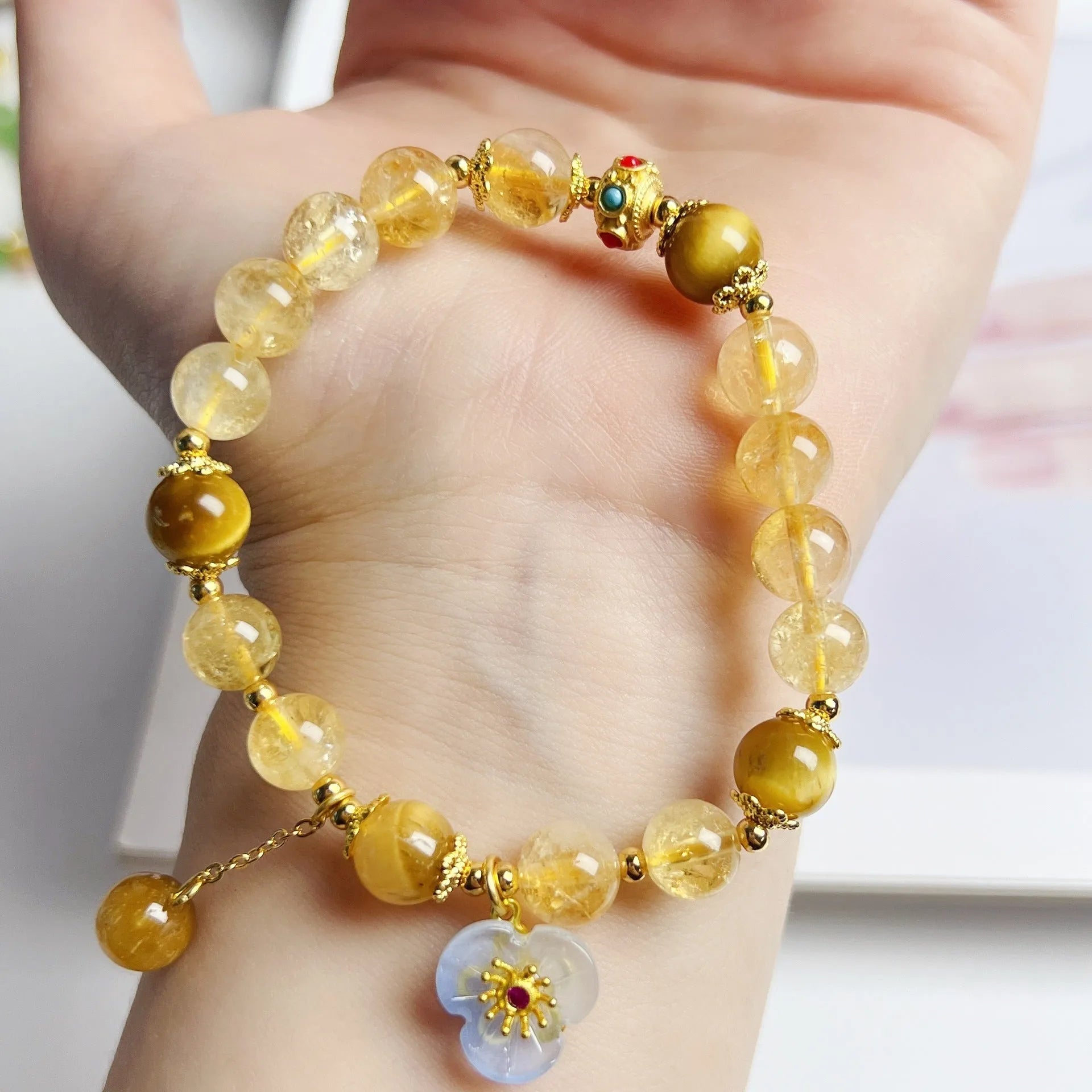 Close-up of a handcrafted citrine crystal bracelet for women with a floral tassel pendant.