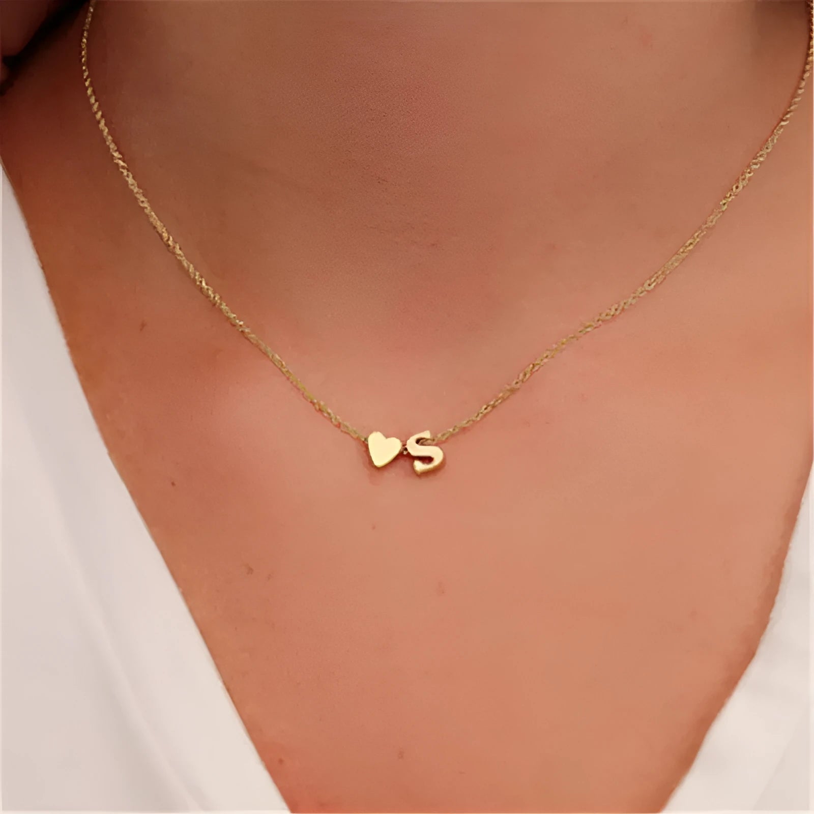 Gold tone peach heart shape pendant with a letter charm on a white background.