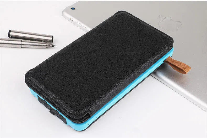 Outdoor solar power bank in black with a solar panel, soft leather finish, and LED light on a grassy field.