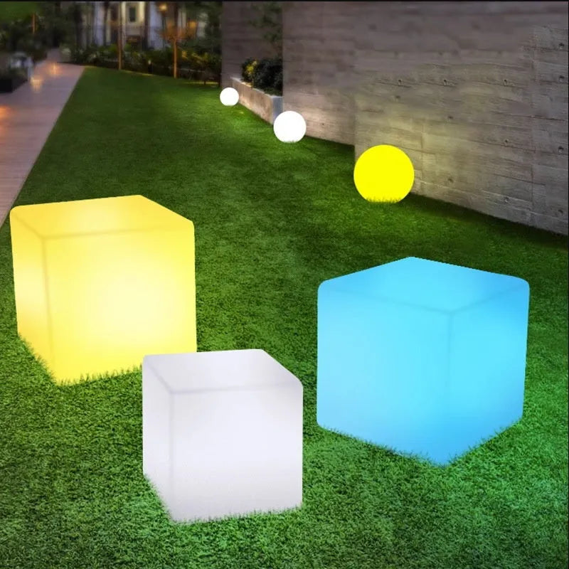 Modern square LED cube light stool in a garden setting, showcasing its clean design and luminous top.