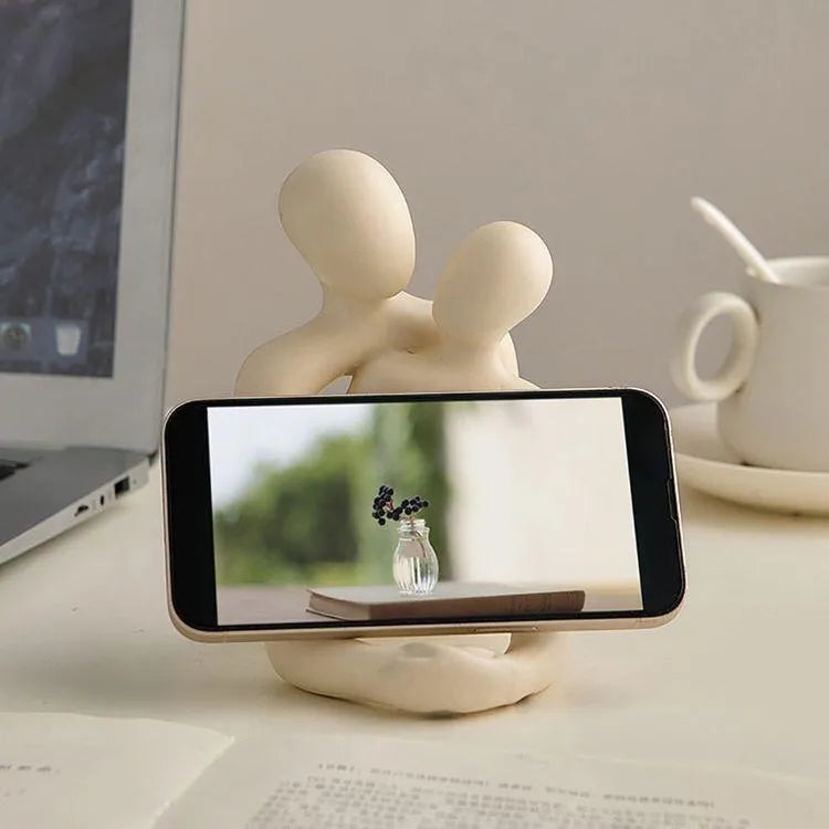 Modern resin couple statue in milky white or gold colour on a wooden surface.