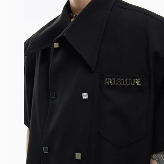 A man's loose-fitting short-sleeved casual shirt in a light colour with a lapel collar and decorative button detail.