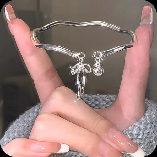 Silver adjustable bracelet with a detailed opening bow charm on a model's wrist, showing the lobster clasp.