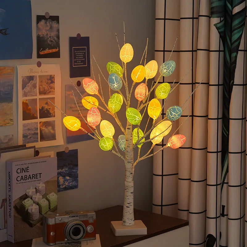 White plastic birch tree Easter decoration with warm white LED lights and hanging coloured eggs on adjustable branches.