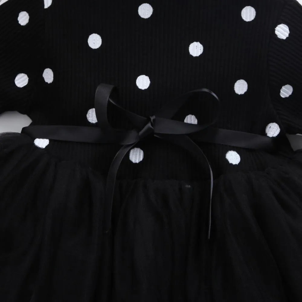 Baby girl wearing a long sleeve black tutu lace dress for a first birthday party.