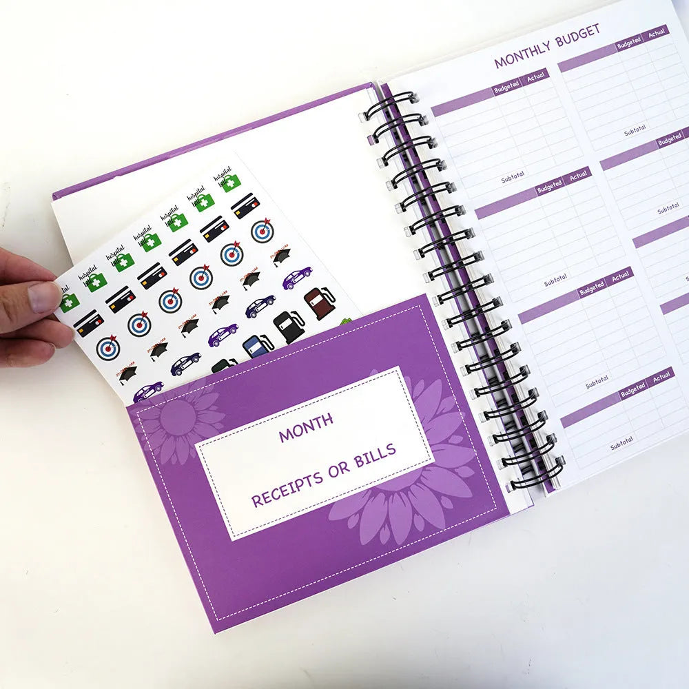 J12 purple coil-bound budget book open showing Daolin paper pages with financial tracking stickers and paper clips