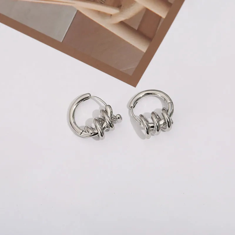 Spiral wound ear clip frosty style geometric earrings in gold colour on white background