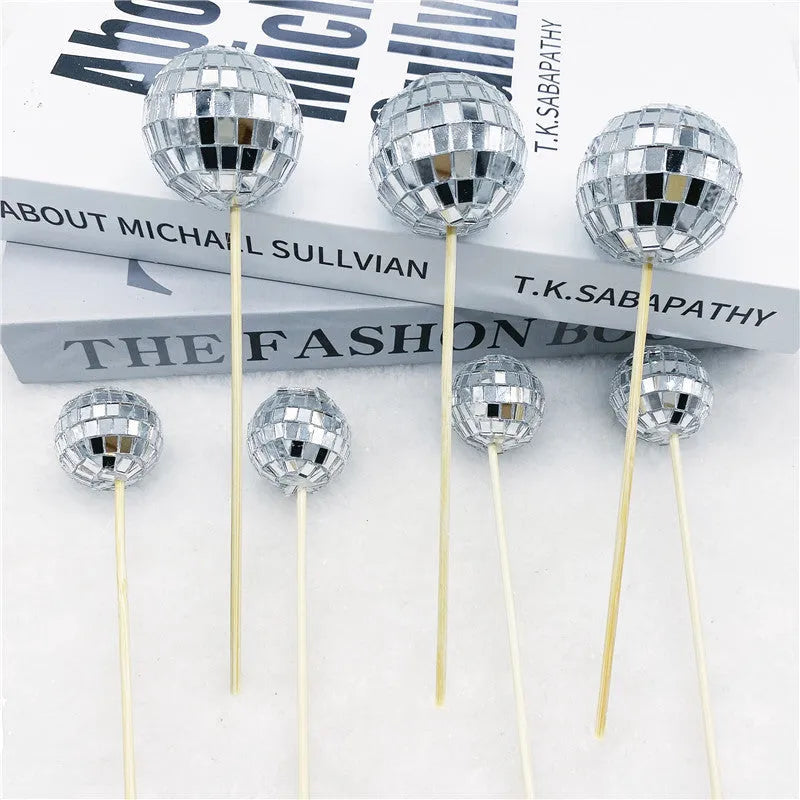 Small glass mirrored disco ball cake decoration attached to a thin wooden stick.