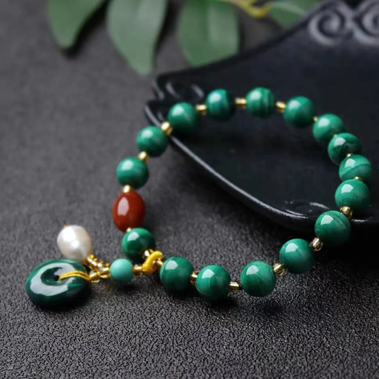 Handmade natural malachite and red agate bracelet with 7-8mm barrel beads on a wrist.