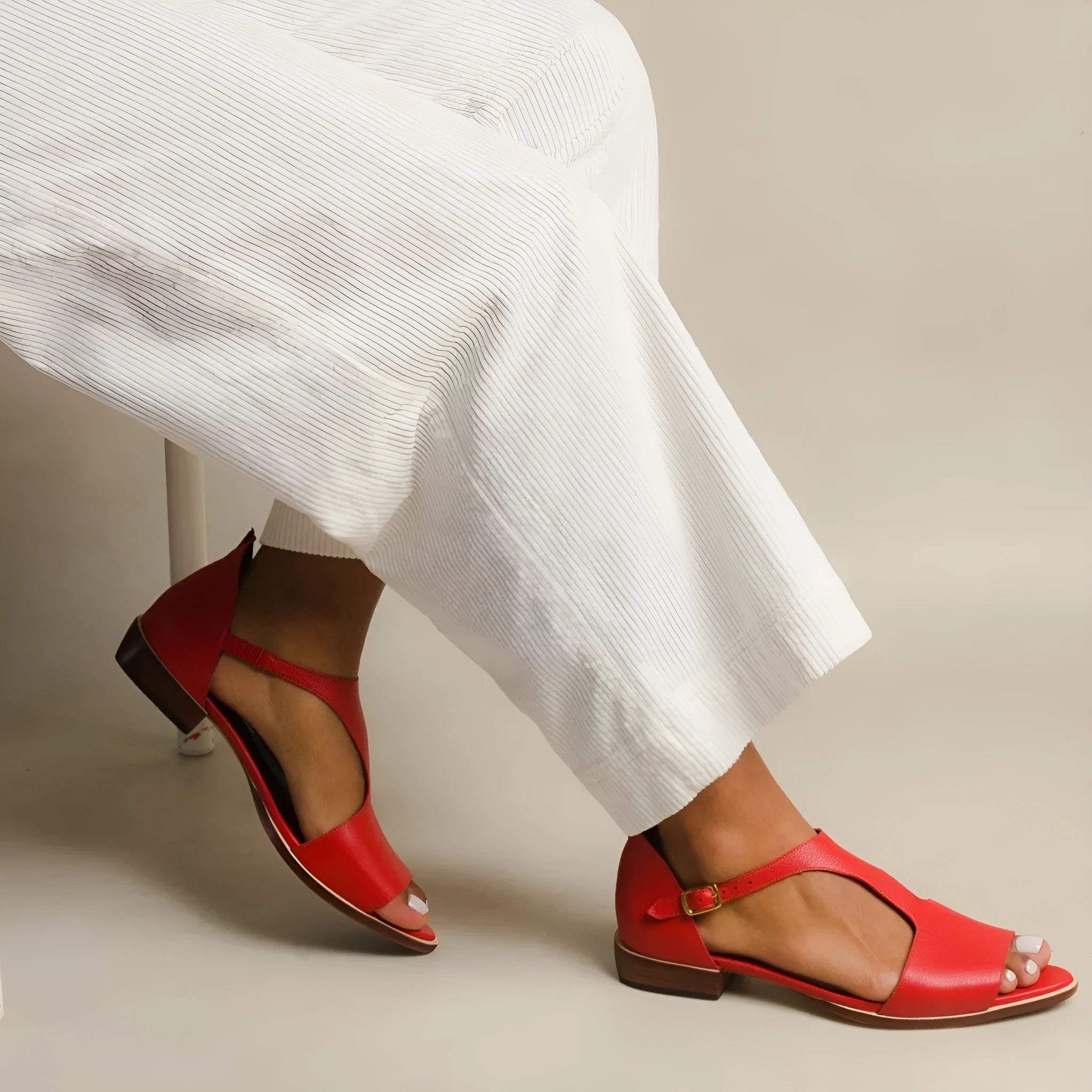 Red women's sandals with a square buckle and herringbone pattern toe strap.