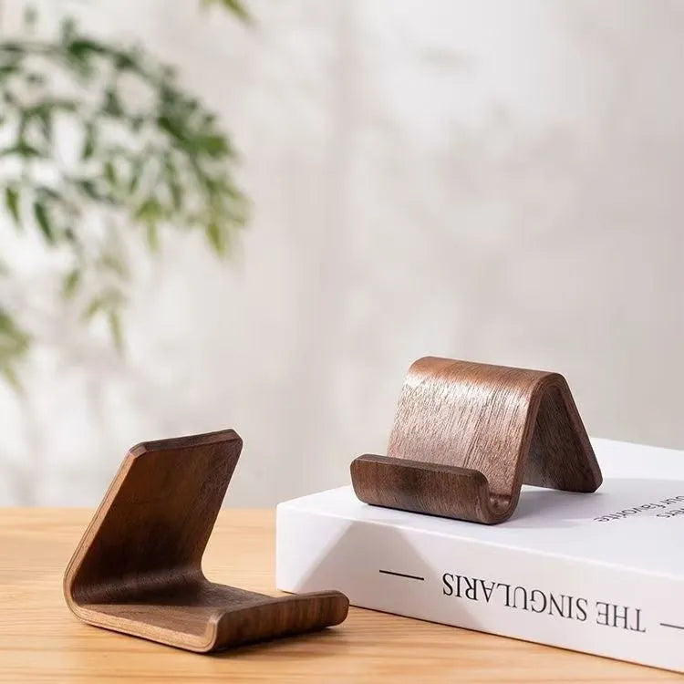 Walnut wooden mobile phone bracket on a desk, with a smartphone placed in the stand