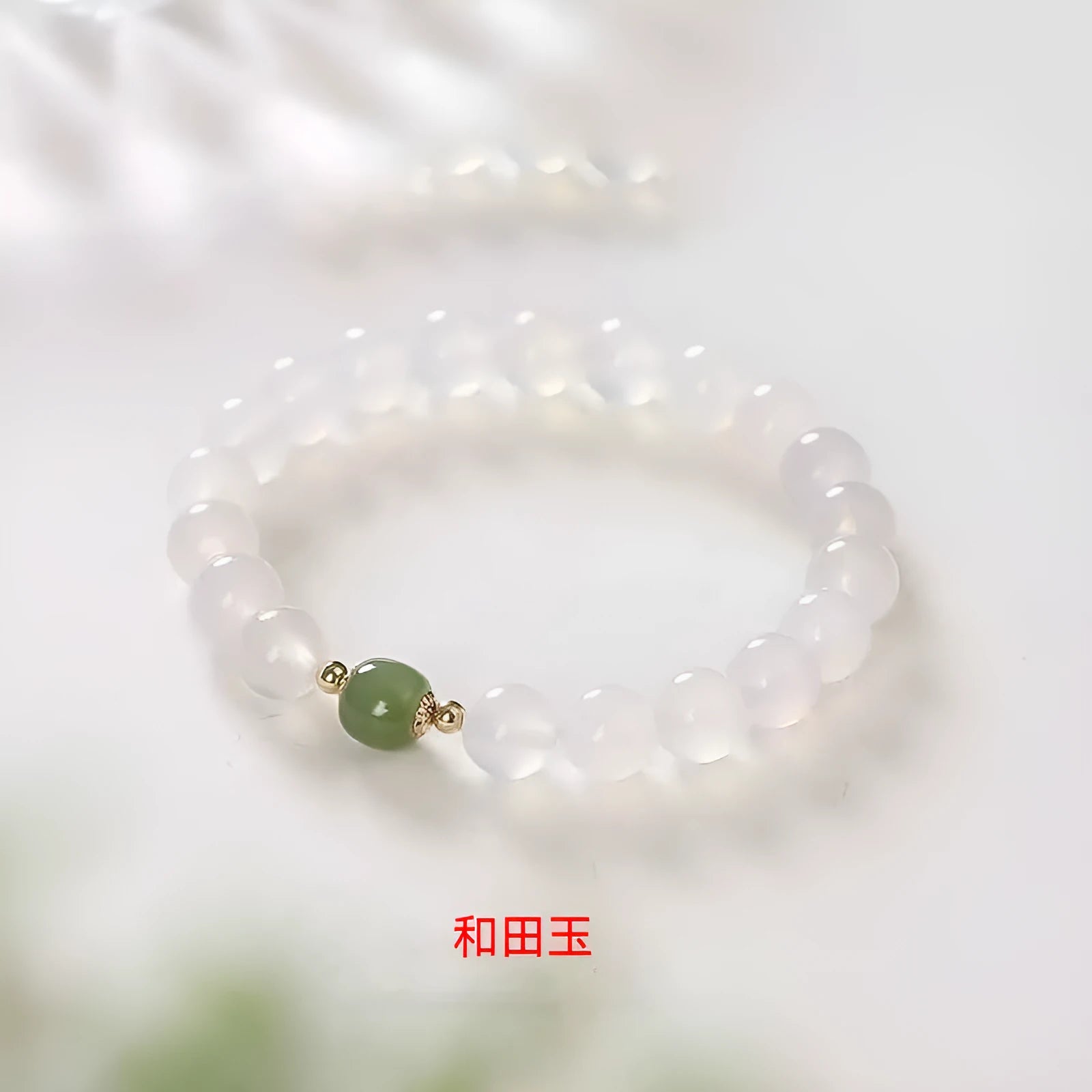 Handmade white agate crystal bracelet with cinnabar details on a wrist, showing 8mm bead size.