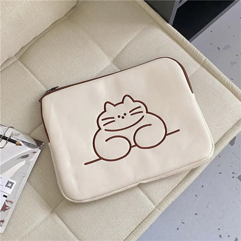Embroidered cat design on a navy blue nylon tablet protective sleeve with a black zipper, shown next to a tablet.