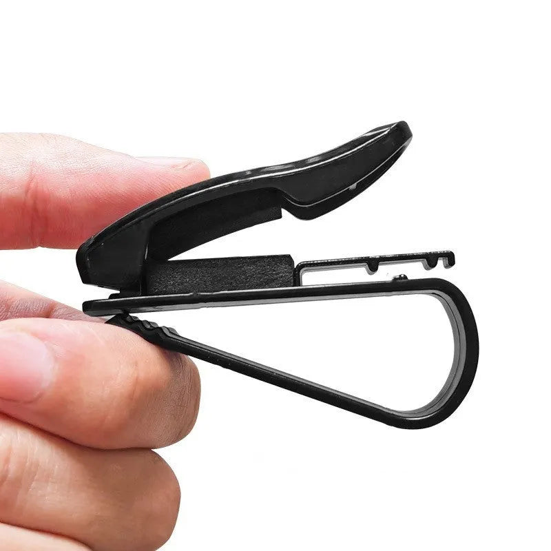 Black plastic multifunctional clip for car sun visors to hold tickets, IDs, or glasses.