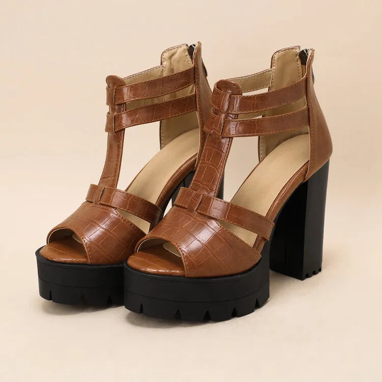 Black platform high heel sandals with a round toe and back zipper on a wooden floor.