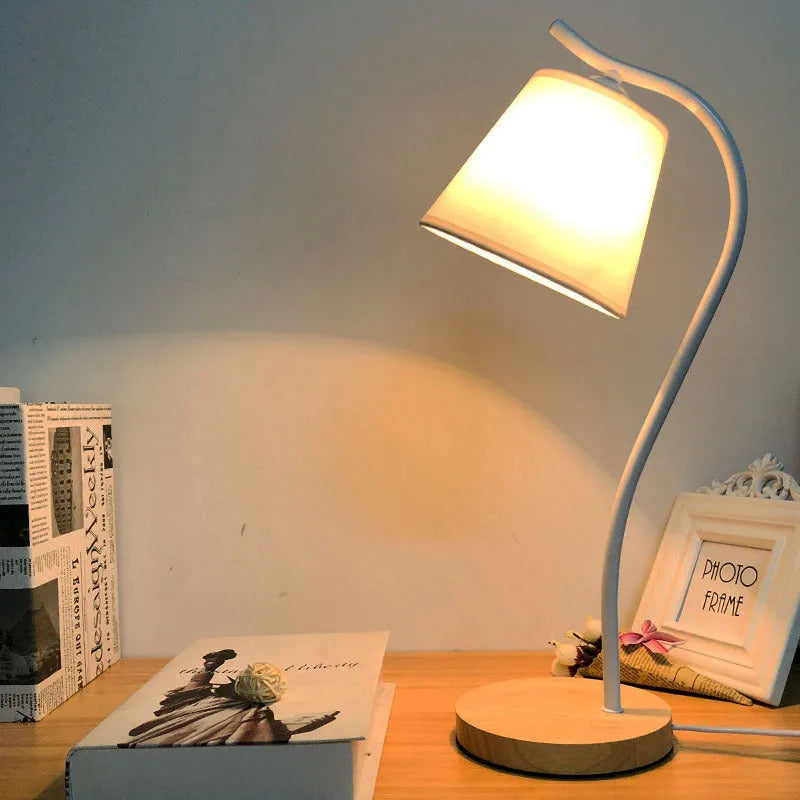 A simple modern Nordic style LED desk lamp with a dimmer switch on a desk.