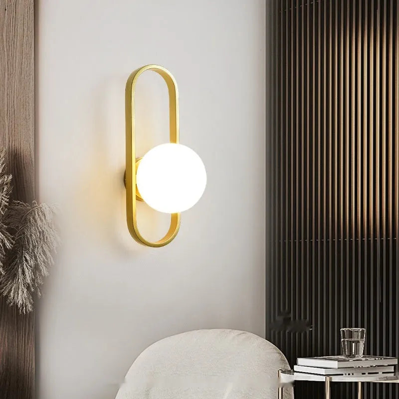 Minimalist black iron wall sconce lamp with glass shade mounted beside a bed.