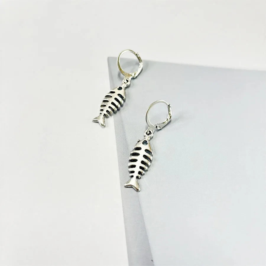Fishbone pendant necklace and matching earrings set with adjustable chain on grey background
