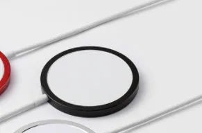 Silver metal Magsafe-compatible magnetic wireless charger for iPhone on a wooden desk
