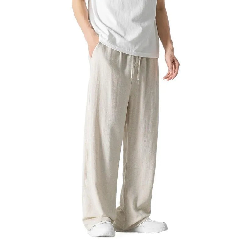 Man wearing beige straight-leg cropped bamboo fibre trousers with a drawstring waist on a summer day.