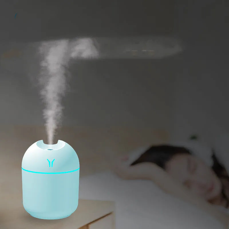 Compact round desktop humidifier with USB cable in ivory white, sky blue, or pink.