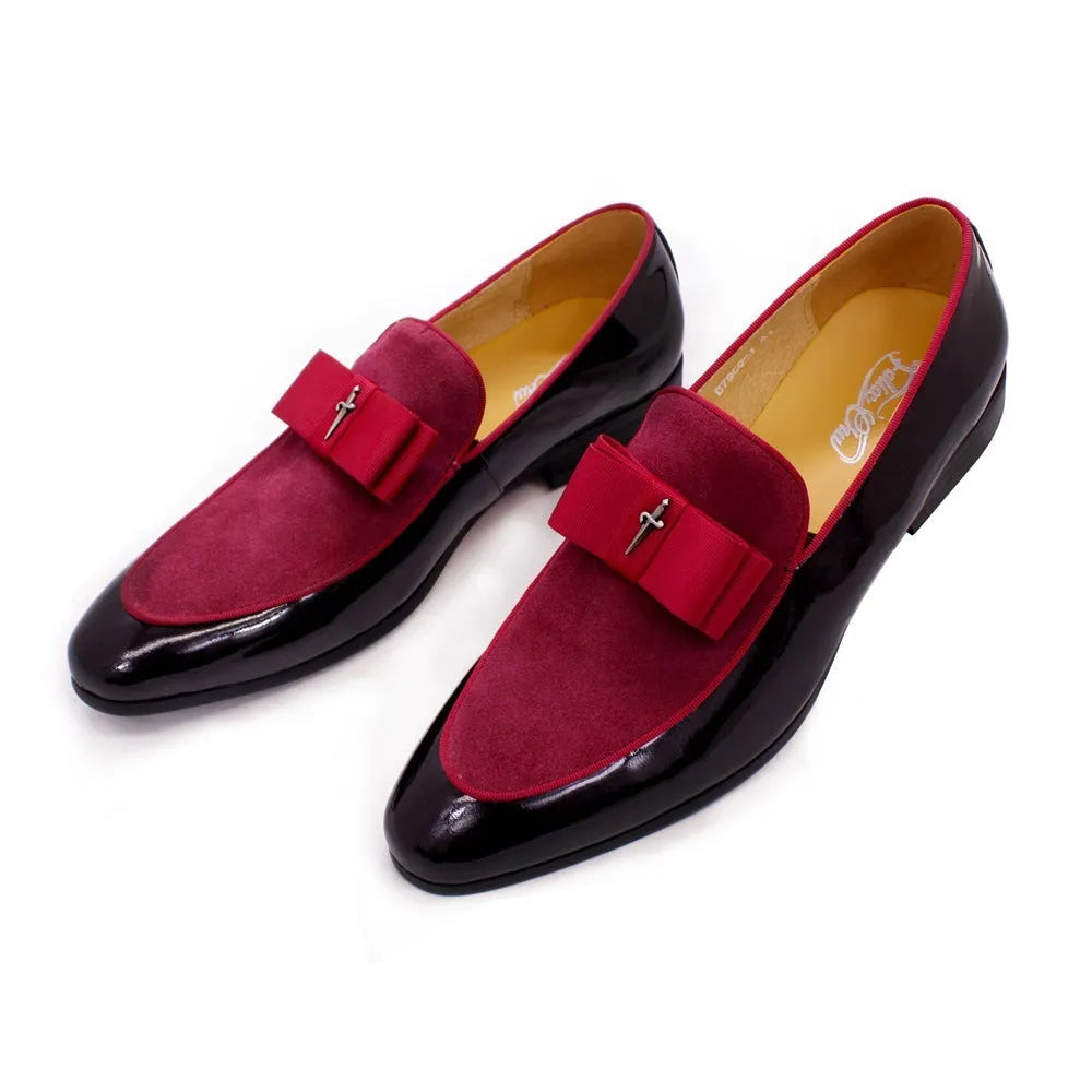 Men's black and brown tassel loafers with a matte and patent leather upper on a wooden floor.
